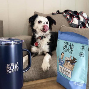 A dog sits beside a coffee mug on a table, creating a cozy and inviting atmosphere.