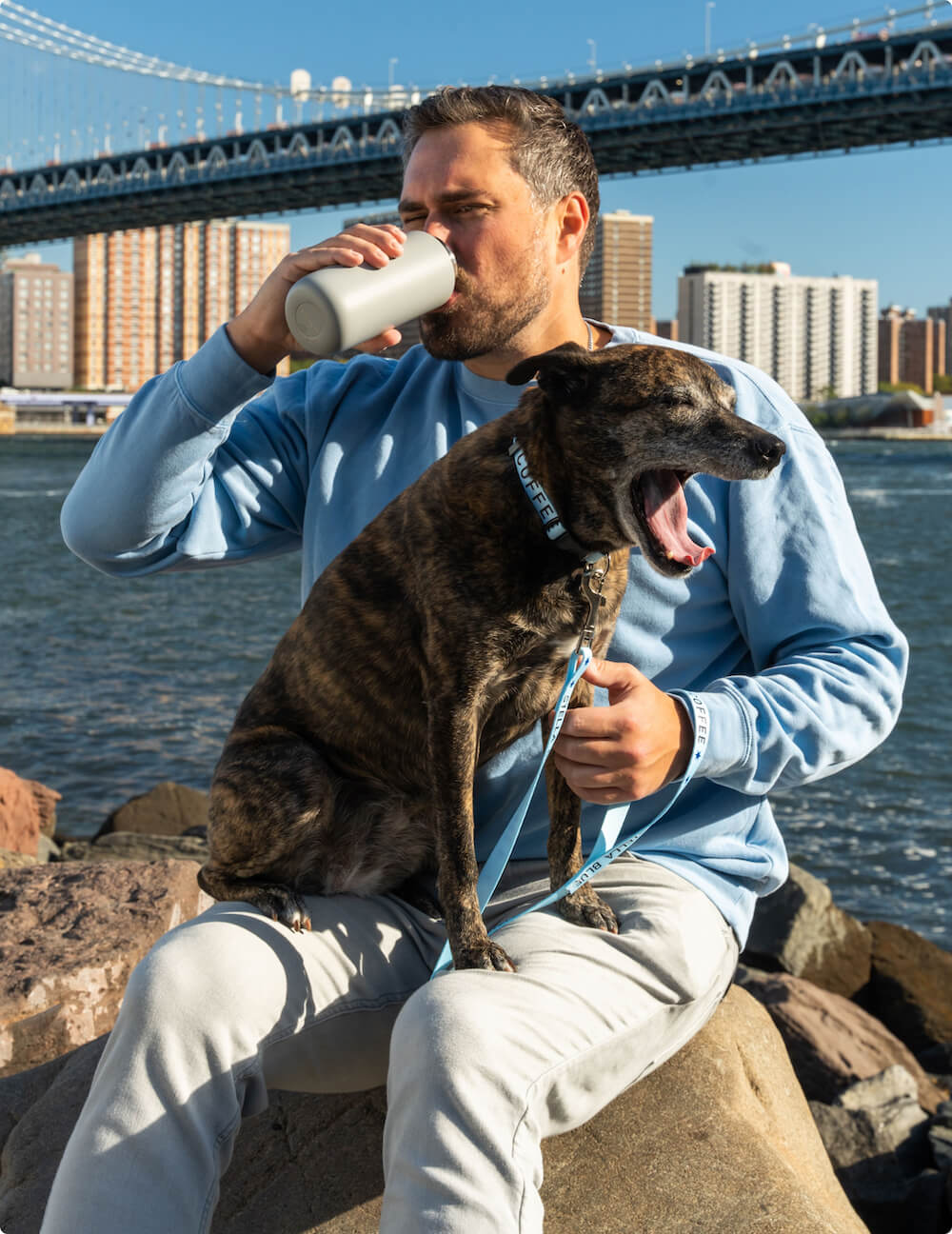 Big Kat drinking a thermos while Stella Blue yawns in his lap