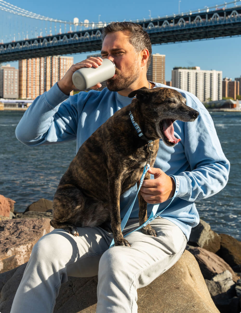 Big Kat drinking a thermos while Stella Blue yawns in his lap