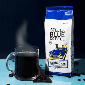 A vibrant electric blue coffee cup filled with rich, steaming Stella Blue coffee, set against a simple background.